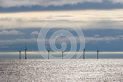 Offshore wind farm turbines on sea horizon with cloudscape background Stock Photo