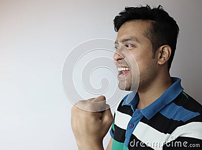 Oh yes. left side face of an asian man with clinched fist showing delighted expression looking towards a copy space with grey Stock Photo