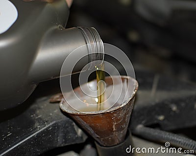 Oil change in the engine of the car. Filling the oil through the funnel. Car maintenance station. Stock Photo