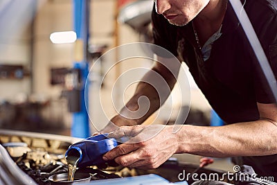 Oil replacing maintenance. Car engine lubricants changing in auto service. Focus on pouring oil into engine. Copy space Stock Photo