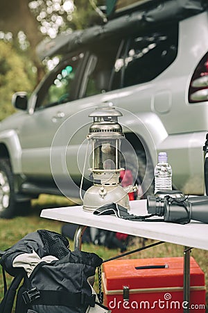 Oil lamp and binoculars over camping table Stock Photo