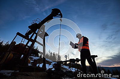 Oil man controlling work of petroleum pump jack. Stock Photo