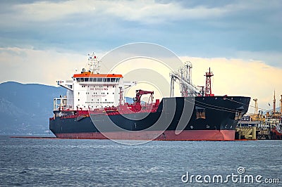 Oil tanker bringing its cargo in a tank storage facility. Stock Photo