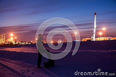 Oil worker in oilfield. Pump jack and engineer on a winter sunset sky background. Western Siberia. Stock Photo