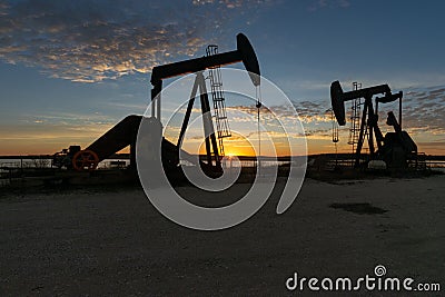 Oilfield pump jacks silhouetted against a morning sunrise Stock Photo