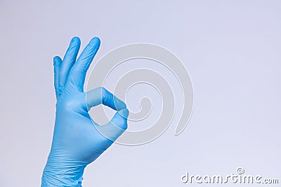 Ok sign is showed by left man hand in a blue medical glove on a white background. Okay Stock Photo