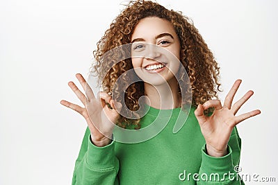 Okay, very well. Smiling beautiful girl, young woman showing ok, zero gesture with happy face, approve, like smth Stock Photo