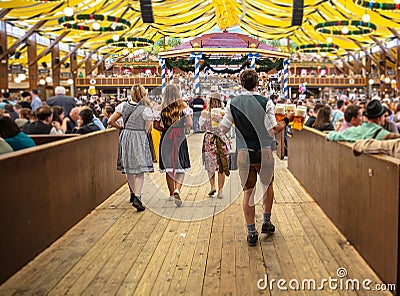 Oktoberfest, Munich, Germany. Waiter holding beers, tent interior background Editorial Stock Photo