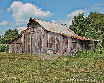 An old abandoned barn in the country with a blue sky and white clouds Stock Photo