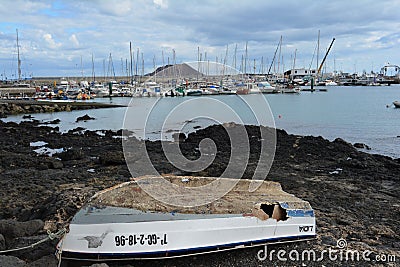Old abandoned boat on the coast. Yacht pier at the background Corralejo, Fuerteventura, Spain Editorial Stock Photo