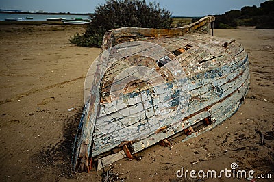 Old abandoned damaged fishing boat turned upside down at the beach Stock Photo