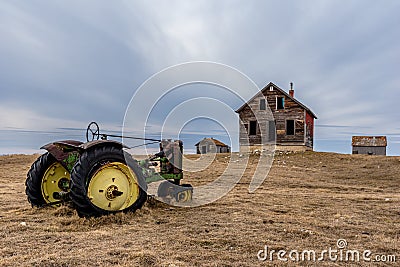 Old abandoned farmhouse overlooking a vintage tractor on the prairies in Saskatchewan Editorial Stock Photo