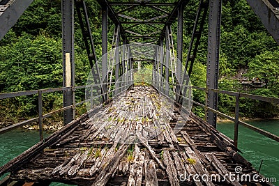 Old abandoned iron bridge spans over green river Stock Photo