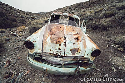 OLd abandoned rusty retro car in the desert with bullet holes in metal. Stock Photo