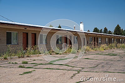 Old, abandoned seedy motorcourt style motel, decays in the sun. Weeds overgrowing in the parking lot Stock Photo