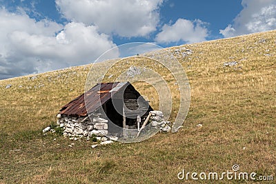 Old abandoned shepherd's hut in middle of pasture on slope of Vlasic mountain Stock Photo