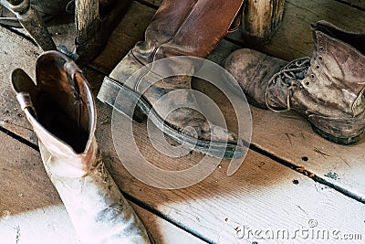 Old dusty dirty cowboy boots sitting on a wooden floor Stock Photo