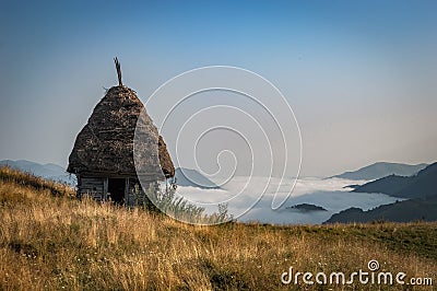 Old abandoned wooden cabin on top above a valley in fog Stock Photo