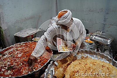 Old age Shopkeeper Selling very famous halwa and paratha at Zakaria Street Editorial Stock Photo