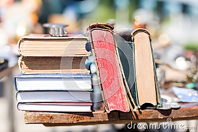 Old aged books at flea market. Vintage retro literature on wooden table outdoors. Street swap meet background Stock Photo