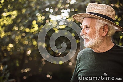 Old aged man standing in profile against background of trees Stock Photo