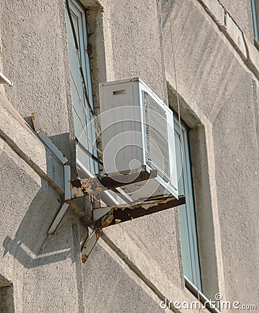 An old air conditioner near a window on the wall of a building Stock Photo