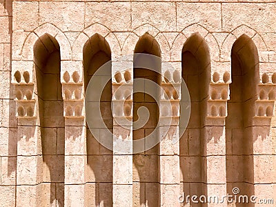 An old ancient yellow stone strong wall with arches in patterns and columns in an Arab Muslim Islamic warm tropical country in the Stock Photo