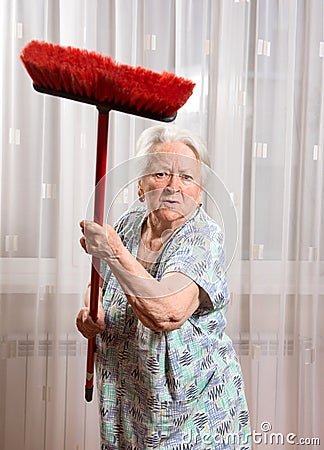 Old angry woman threatening with a broom Stock Photo