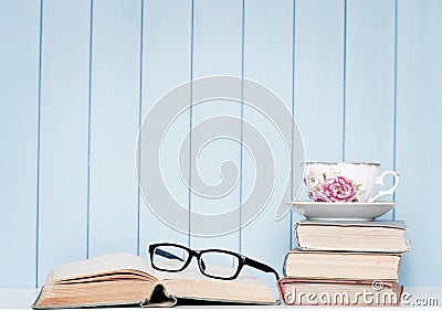 Old antiquarian books, glasses and china cup on the bookshelf Stock Photo