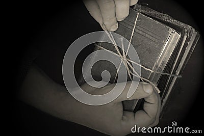 Old antique books stacked in a pile being tied together by a man. Stock Photo