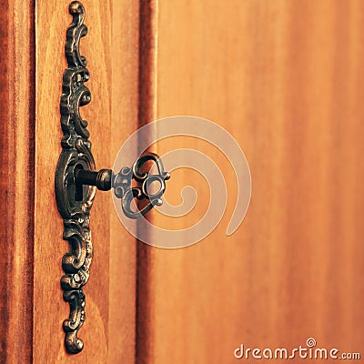 Old antique key in the lock. Wooden furniture Stock Photo