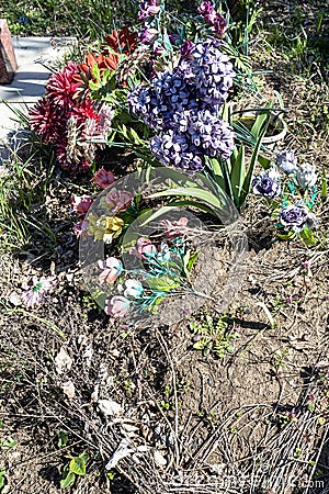 old artificial flowers on grave mound in cemetery Stock Photo