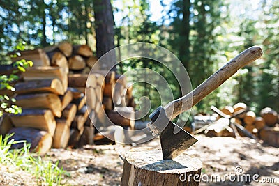 Old axe standing against a piled pieces of firewood Stock Photo