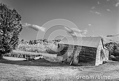 Old barn, garage and car in field black and white Stock Photo