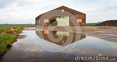 Old barn reflected in a puddle of water Stock Photo