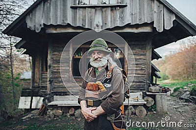 Old bearded forester posing in front of old wooden hut Stock Photo