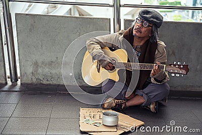 Old beggar play guitar for money donation Stock Photo
