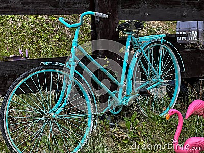 An old bicycle, painted in a bright solid color, stands by the fence as a decorative element Stock Photo