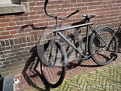 An old Bicycle standing next to a stone wall. City landscape of Amsterdam Stock Photo