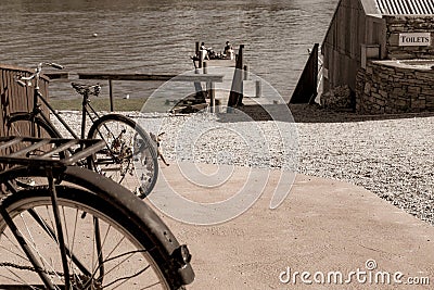 Old bicyle wheels in street in small town with group four youth in distance on jetty Editorial Stock Photo