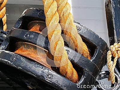 Old black double pulley with strong rope closeup. Stock Photo
