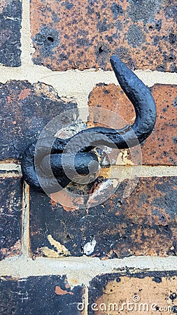 Old Black Metal Hook on a Brick Wall Stock Photo