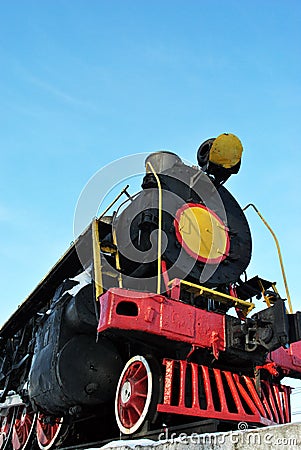 Old black train with red elements covered with snow, standing on platform against blue sky background Stock Photo