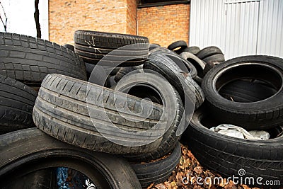 old black used car tires heaped with leaves Stock Photo