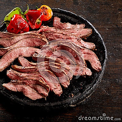 Old blackened plate with sliced flank steak Stock Photo