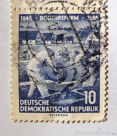 An old blue east german postage stamp with building workers on a construction site Editorial Stock Photo