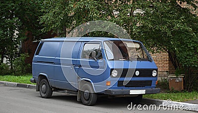 An old blue minibus is parked near the lawn Stock Photo