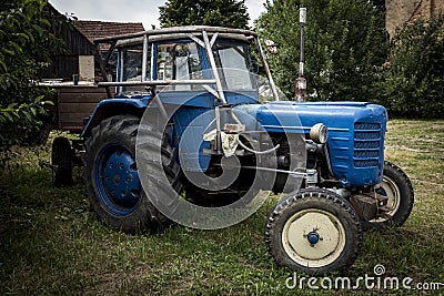 Old blue tractor standing in the garden Stock Photo