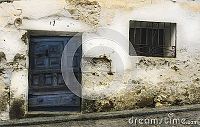 Old blue wooden door and wrought iron window on white lime wall Stock Photo