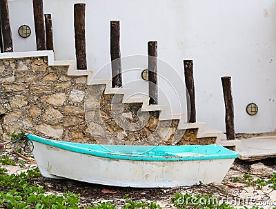 Old boat on beach by rock stairs and white wall Yucatan Mexico Stock Photo